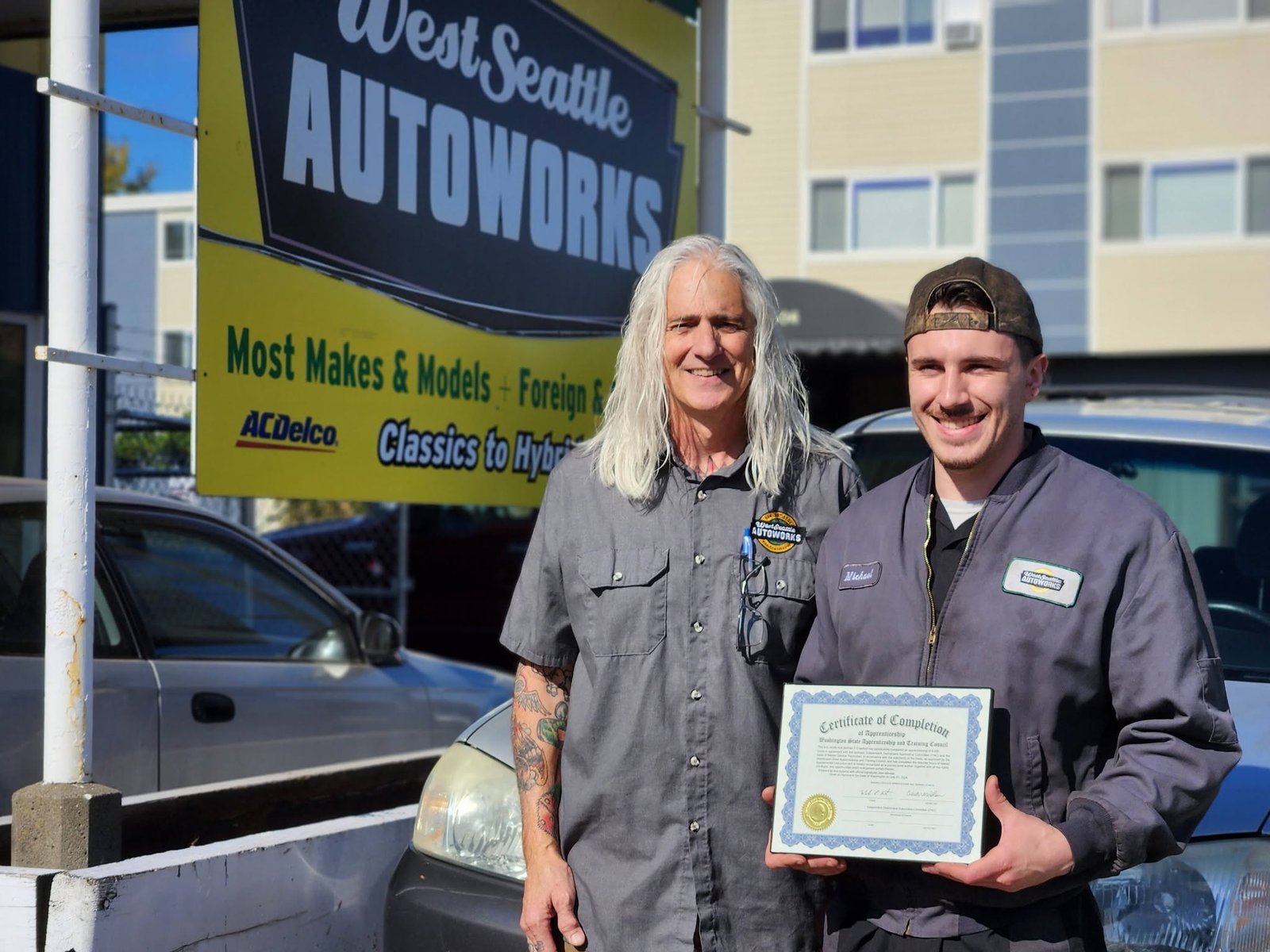 A newly certified apprentice with his Certificate of Completion and his mentor at the shop.