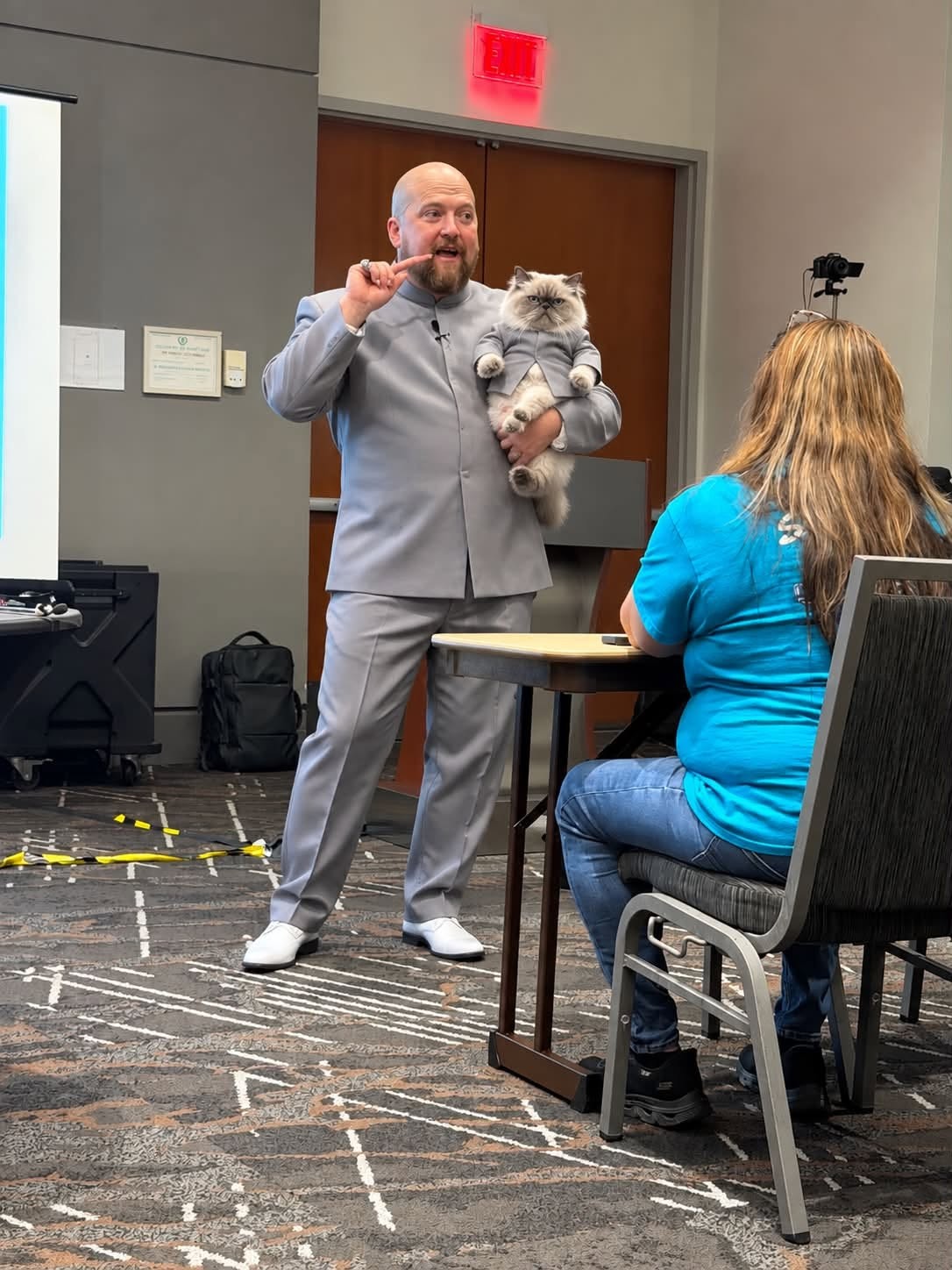 Mike Allen in a gray suit holding a fluffy cat that is wearing a matching gray suit.
