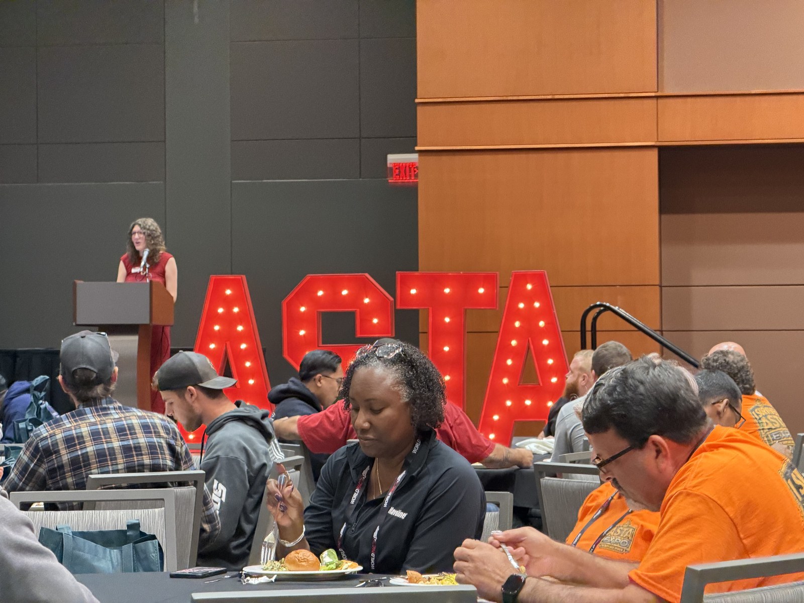 Attendees seated at tables during a session at ASTA Expo 2026, with the lit ASTA marquee letters behind them.