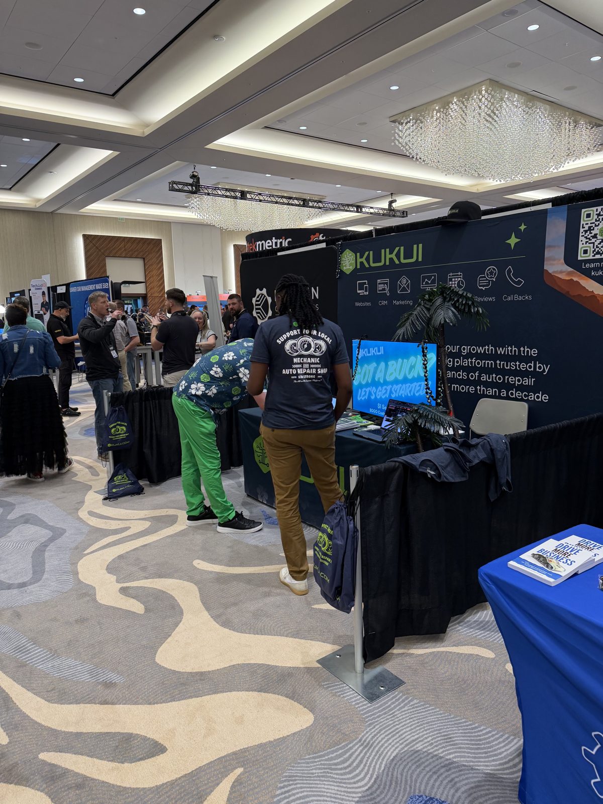 The Tektonic 2026 expo floor, with the Tekmetric and KUKUI booths and shops walking the aisles