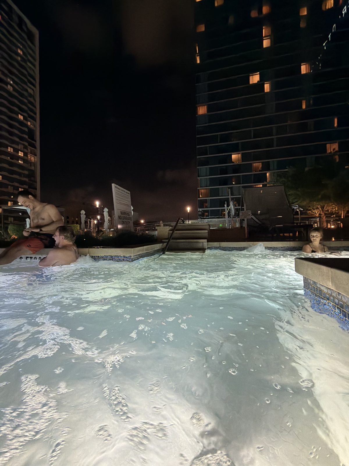 A rooftop pool at night during Tektonic 2026, with the Houston skyline lit up behind it